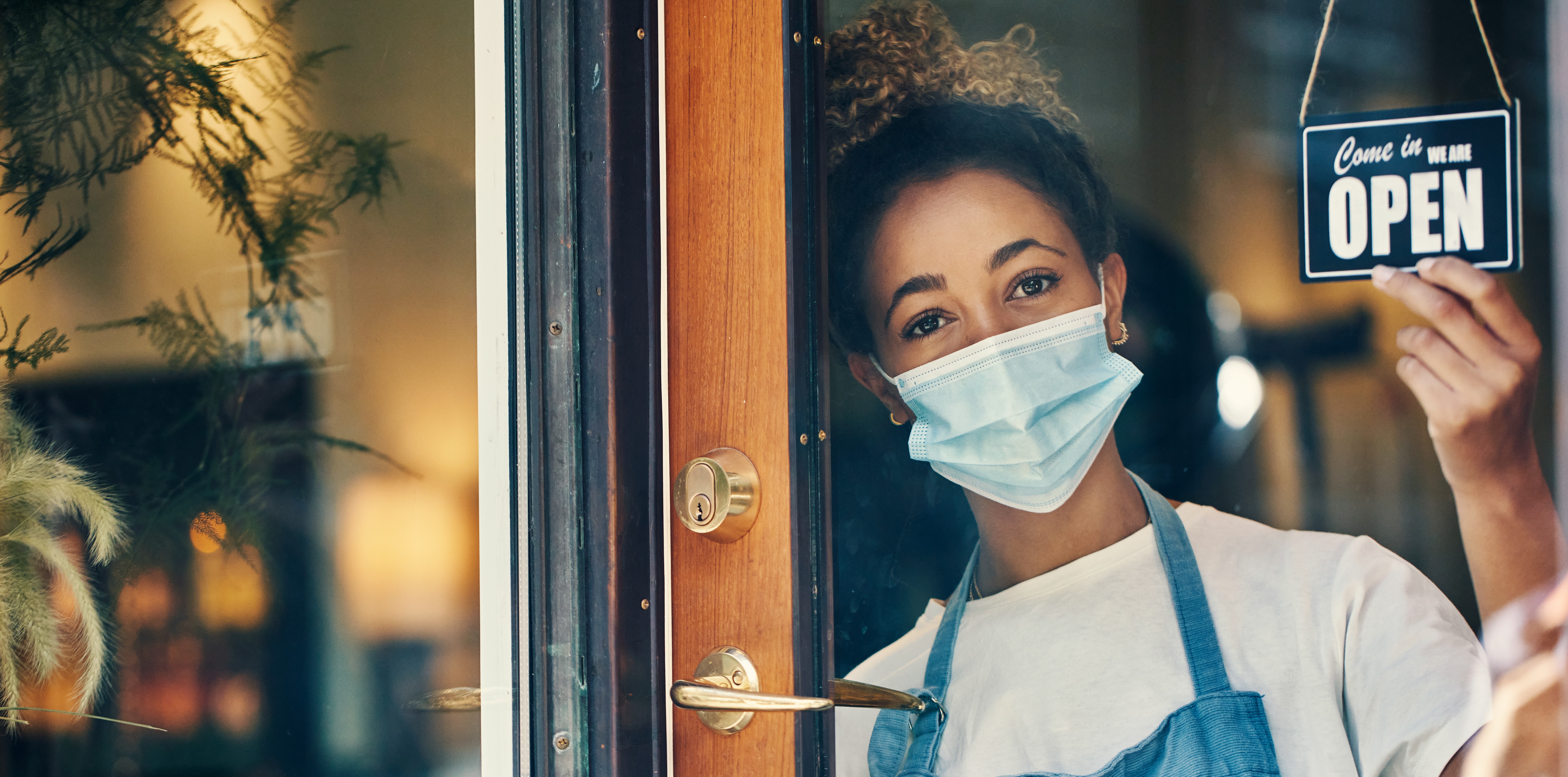 woman opening her store wearing a mask 